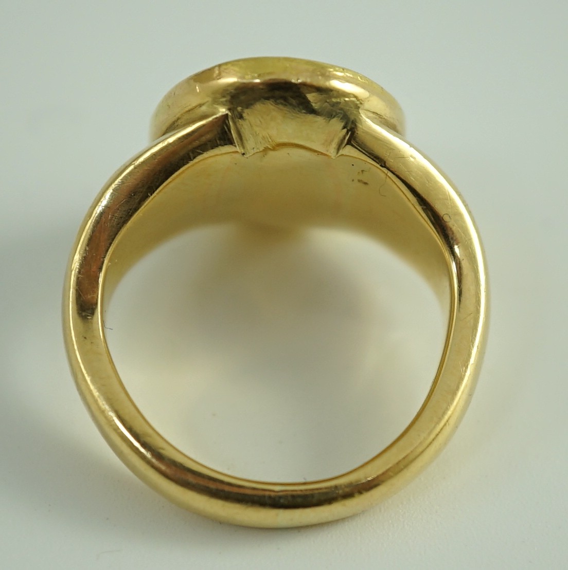 A Roman oval intaglio amethyst, carved with a figure with staff and pedestal, set in a later heavy gold ring mount